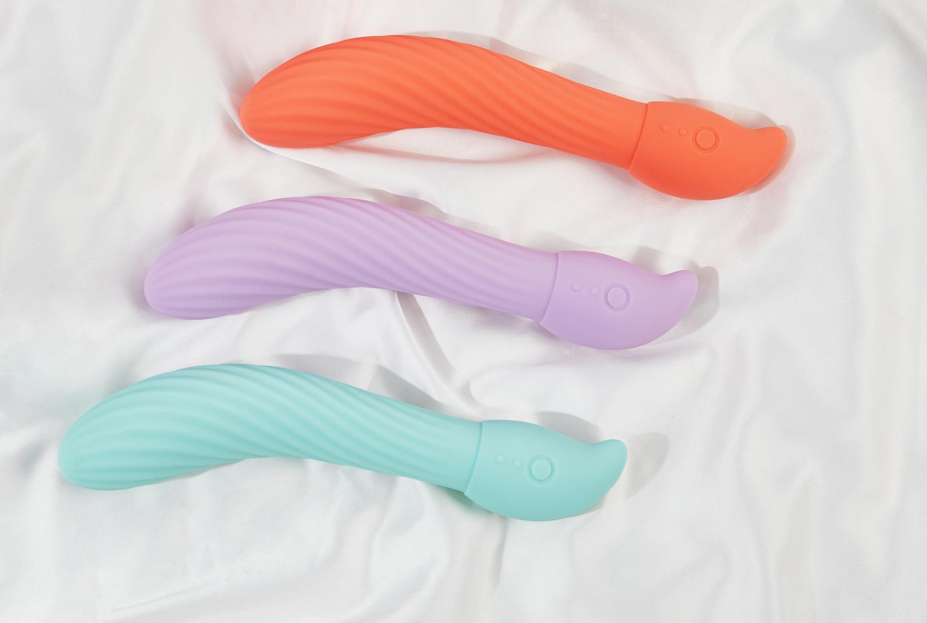 Woman holding blue and pink silicone vibrators in thoughtful moment