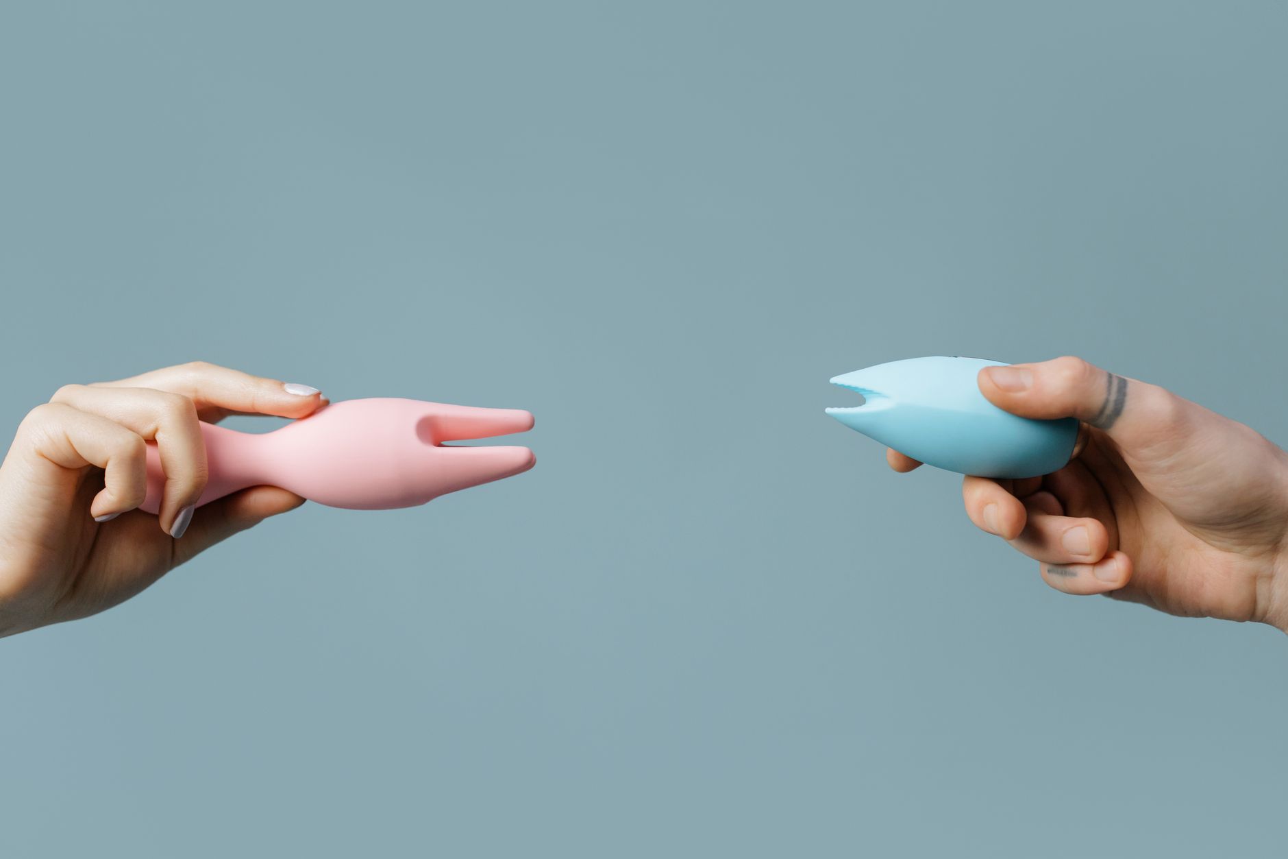 Hands holding pastel-colored vibrators, representing tools for relaxation and pleasure
