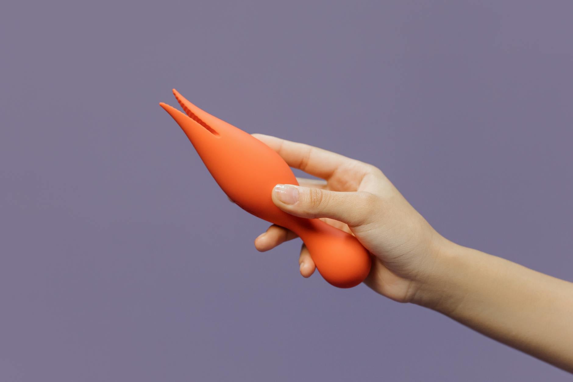 A hand holding a vibrant vibrator against a minimalistic backdrop, symbolizing the journey of reconnecting with pleasure
