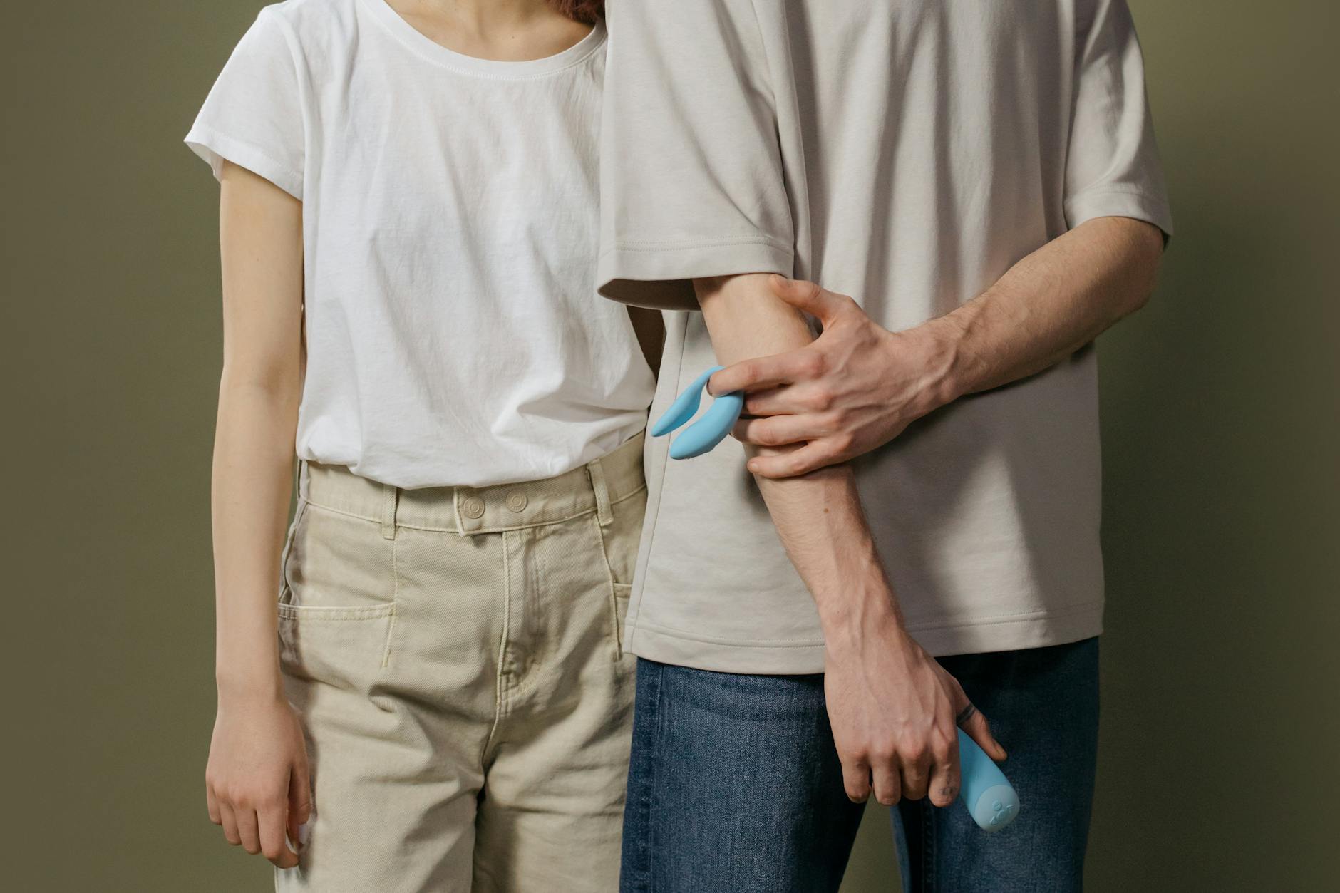 Close-up of hands holding a sleek blue vibrator against a purple background, symbolizing reconnection and healing