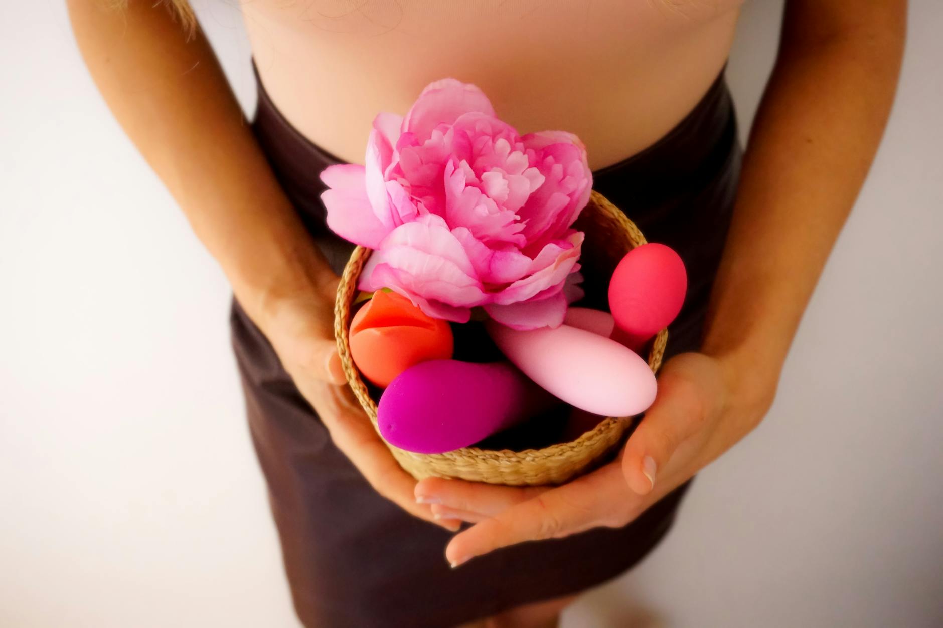 Hand selecting a colorful vibrator from an array of clitoral toys arranged on a table